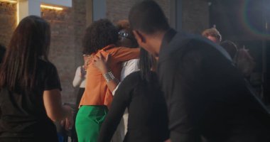 Çeşitli cemaat üyeleri modern bir kilise ortamında kucaklaşıp gülümsüyor, bir topluluk, bağlantı ve paylaşılan maneviyat duygusu yaratıyorlar.