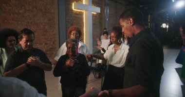 Dua eden cemaatin yakın çekimi, ruhani bağlantıda tutulan eller, modern evanjelik kilise ortamında ibadet liderleri, inançla birleşen topluluk.