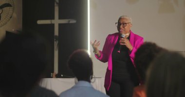 Cemaate hitap eden, mikrofon tutan, haç önünde güçlü bir vaaz veren, kilise toplantısında dikkatle dinleyen çeşitli dinleyiciler.