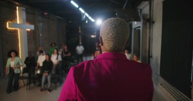 Papaz cemaati ibadete teşvik eder, ellerini kaldırarak dua eder, modern evanjelik kilise ortamında ruhsal bağlantı kurar, Hıristiyan birliği sağlar.