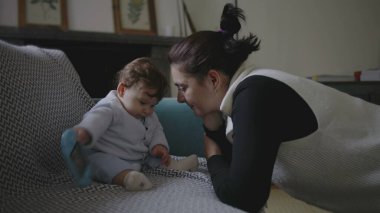 Anne nazikçe bebeğe eğiliyor, yakınlaşma sırasında samimi ve eğlenceli anları paylaşıyor, erken çocukluk iletişimini ve keşifleri teşvik ediyor, ev ortamını besliyor..