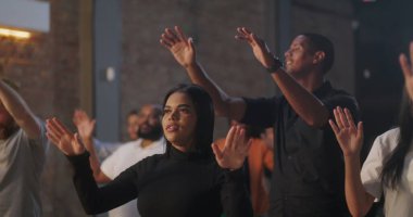 Çeşitli bireylerin dua ederek el kaldırdığı ibadet grubu, gözler kapalı, duygusal ifadeler, Hıristiyan inanç topluluğu, maneviyat, ibadetteki birlik, kilise kurmak.