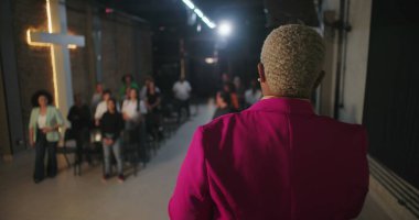 Papaz cemaati ibadete teşvik eder, ellerini kaldırarak dua eder, modern evanjelik kilise ortamında ruhsal bağlantı kurar, Hıristiyan birliği sağlar.