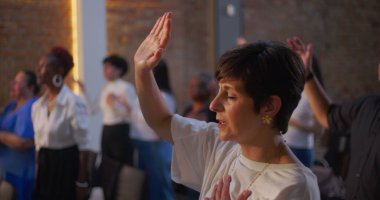 Kilisede manevi bir toplantı sırasında, sadakat ve inançla bağlantıyı ifade eden, yürekten duygularla el kaldıran bir kadın.