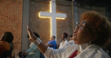 Kilise ayini sırasında ibadet eden bir kadın, sadakat içinde kapalı gözler, arka planda aydınlanmış haç ve cemaat, maneviyat ve inanç ifade eden