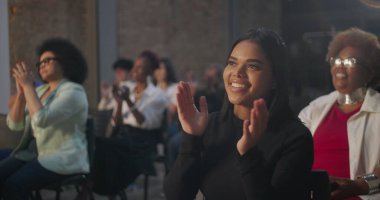 Bir grup insan ibadet ederken neşeli ifadelerle el çırpıyor, dingin bir kilise ortamında inanç ve birliği kutluyorlar, parlayan yüzler ve ruhanilik vurgulanıyor