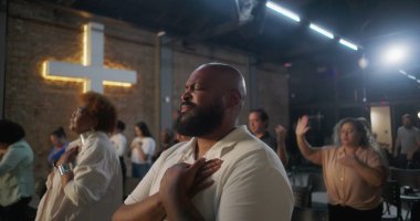 Yürekten ibadet eden bir adam, arka planda parlayan bir haç, kutsal kilisede derin manevi yansıma, inanç ve duygusal bağlantı.