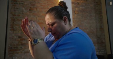 Kilise ayini sırasında dua eden ve ibadet eden İspanyol bir kadın. Gözler bağlılık içinde kapalı, arka planda tuğla bir duvar, ruhsal bir bağlantı.