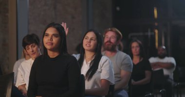 Bir kilise etkinliğinde seyirci, ön planda dikkatle dinleyen bir kadın, arka plandaki diğerleri de odaklanmış ve meşgul.