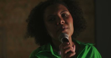 Afrika kökenli bir kadın, kilise toplantısı sırasında tutkuyla şarkı söylüyor, mikrofon tutuyor, ruhani ibadet performansı, duygusal ruhsal bağlantı
