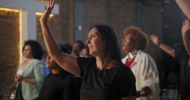 Kilisede ruhani bir toplantı sırasında ibadet için el kaldıran bir grup insan cemaatin yanında sadakat ve inanç ifade ediyorlar.