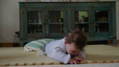 Bebek paspasın üzerinde yatıyor, elleriyle dokunmuş ve keşfetmiş, sakin bir ev ortamında dokunsal bağlılık ve duyusal gelişime odaklanmış..