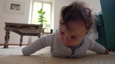 Bebek yerde yatıyor, iki koluyla yukarı itiyor, merakla ileri bakıyor, rahat bir ev ortamında çevreyi keşfediyor, emeklemeyi öğrenmenin ilk aşamaları..