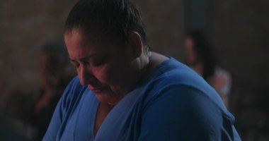 Başı sessizce dua eden, mavi giyen, ruhani yansımaya dalmış ve ibadet sırasında inançla barışçıl bir bağ kuran bir kadın.