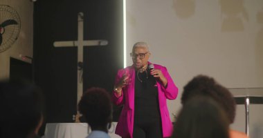 Cemaate hitap eden, mikrofon tutan, haç önünde güçlü bir vaaz veren, kilise toplantısında dikkatle dinleyen çeşitli dinleyiciler.