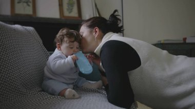 Anne nazikçe bebeğe eğiliyor, yakınlaşma sırasında samimi ve eğlenceli anları paylaşıyor, erken çocukluk iletişimini ve keşifleri teşvik ediyor, ev ortamını besliyor..