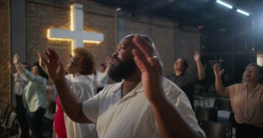 Çeşitli gruplar kilise ayini sırasında el kaldırıyor, arka planda çapraz aydınlanma, övgü, neşe ve ruhsal bağlantı ifadeleri.