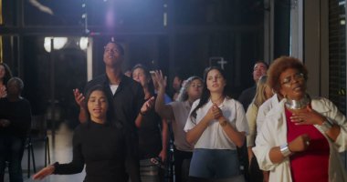 Kilise ortamında grup ibadeti, dua eden, el kaldıran, ruhani bağlantı ve inanç, içeride sadakat ve birliği ifade eden çeşitli gruplar.