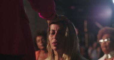 Vaiz kadını ruhani törenle kutsadı, gözleri kapalı, derin tapınma ve inanç, duygusal bağlılık anı çeşitli Hıristiyan ayinleriyle çevrili.