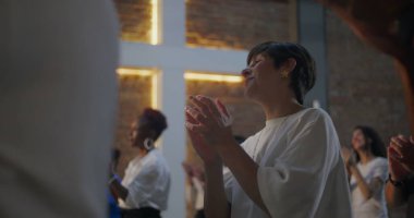 Kilisedeki çeşitli gruplar arasında el çırpan, arka planda aydınlanan haç, inanç, maneviyat ve neşe dolu bağlar.