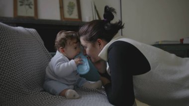 Anne nazikçe bebeğe eğiliyor, yakınlaşma sırasında samimi ve eğlenceli anları paylaşıyor, erken çocukluk iletişimini ve keşifleri teşvik ediyor, ev ortamını besliyor..