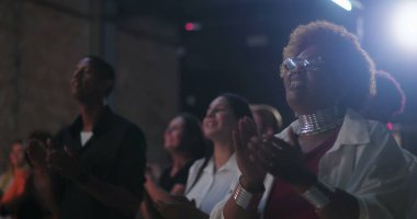 Evanjelik kilise ayini sırasında alkış tutan ve ibadet eden cemaat, neşeli ifadesi, gözlüğü, canlı saçı ve takısı olan Afro-soyundan gelen kadın, inanç kutlamaları.