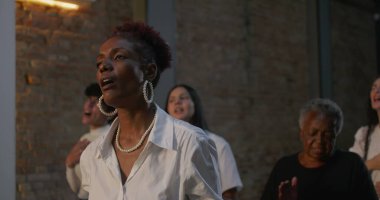 İbadet sırasında insanlar tutkuyla ve inançla şarkı söylüyor. Aydınlanmış haçın önünde duruyorlar. Ruhaniliği, bağlılığı ve toplumsal bağlantıyı temsil ediyorlar.