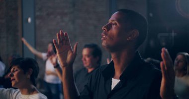 Kilisede ruhani bir toplantı sırasında yürekten dualarla el kaldıran bir adam sadakat ve inançla bağlılık gösteriyor.