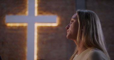 Kilise ortamında ibadet eden kadın profili, arka planda aydınlanma, inanç, maneviyat ve çeşitli grup ortamlarında barışçıl yansıma.