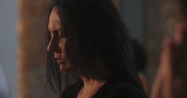 Uzun siyah saçlı, sessiz tefekkür eden bir kadın, gözleri kapalı, ruhani olaylar sırasında huzurlu ve yansıtıcı bir ifade, içsel inanç ve meditasyona odaklan.