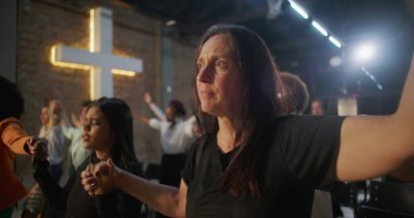 İbadet sırasında el ele tutuşan, birlik ve inancı ifade eden, maneviyatı ve cemaati sembolize eden, içten bir kilise ayini yapan insanlar.