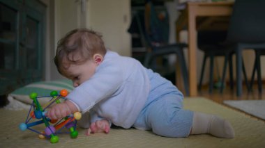 Bebek yerde oturuyor, neşeli bir oyuncakla oynarken neşeyle gülüyor, neşeli ve eğlenceli bir keşifle meşgul, sıcak bir ev ortamında eğlenceli aile vakitlerinin tadını çıkarıyor..