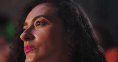 Uzağa dikkatlice bakan bir kadın, yumuşak bir ifadeyle yan profili, derin bir odak ve tefekkür yakalıyor.