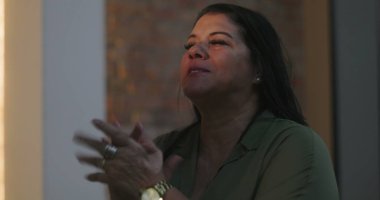 Orta yaşlı Afrikalı Amerikalı kadın ruhani yansıma sırasında el çırpıyor. Barışçıl bir buluşmada derin duygusal bağ ve samimiyet gösteriyor.