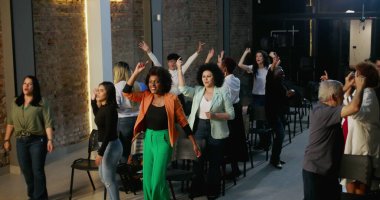 Cemaat ibadet ediyor, el kaldırıyor ve bir kilise ayini sırasında dua ediyor ve kutlama yapıyor. Masa başı olarak tuğla bir duvarda haç parlıyor.