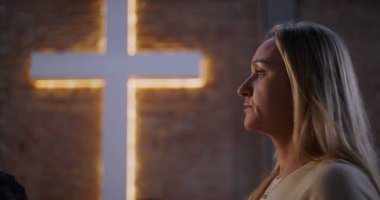 Kilise ortamında ibadet eden kadın profili, arka planda aydınlanma, inanç, maneviyat ve çeşitli grup ortamlarında barışçıl yansıma.