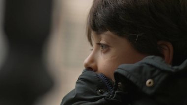 Hareket halindeki bir otobüste sessizce yansıyan genç bir çocuk, düşünceli ifadeye yakın çekim, yolculuk sırasında huzurlu bir düşünce anı