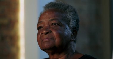 Seyirciler arasında yaşlı bir kadın, ciddi bir ifadeyle, düşünceli bir şekilde uzaklığa bakıyor, düşünceli bir anda yakın plan portresi, dikkat