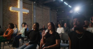 Kilisede düşünceli bir ifadeyle oturan, arka planda aydınlanmış bir haç ve cemaat olan bir kadın, kutsal cemaat toplantısındaki ibadet sırasında bunu yansıtıyor.