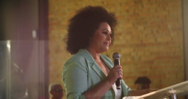 Kürsüde bir konuşma yapan kadın, ruhani bir toplantı, liderlik ve toplumsal bağlantı sırasında tutku ve otorite ile dinleyicilere hitap ediyor.