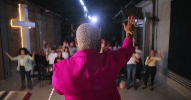 Papaz, ibadet eden ellerini kaldırarak cemaate önderlik ediyor, çeşitli Hıristiyan cemaati modern evanjelik kilisesinde ibadet ve övgüye katılıyor.