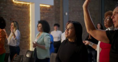 Kilisede ruhani bir toplantı sırasında ibadet için el kaldıran bir grup insan cemaatin yanında sadakat ve inanç ifade ediyorlar.