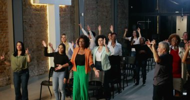 Cemaat ibadet ediyor, el kaldırıyor ve bir kilise ayini sırasında dua ediyor ve kutlama yapıyor. Masa başı olarak tuğla bir duvarda haç parlıyor.