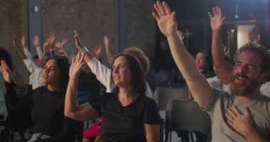 Kilise ayini sırasında dua ederken ellerinizi kaldırın. Bağlılık ve birlik gösteren bir grup insan, kapalı mekanlarda dini toplantılar, ruhsal atmosfer, toplumsal bağ.