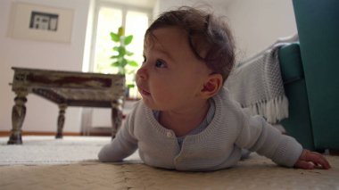 Bebek yerde yatıyor, iki koluyla yukarı itiyor, merakla ileri bakıyor, rahat bir ev ortamında çevreyi keşfediyor, emeklemeyi öğrenmenin ilk aşamaları..