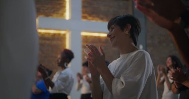 Kilisedeki çeşitli gruplar arasında el çırpan, arka planda aydınlanan haç, inanç, maneviyat ve neşe dolu bağlar.