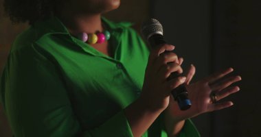 Afrika kökenli kadınların mikrofon tutarken el çırpışları. Evanjelik kilise ibadetleri sırasında, anlamlı jestler, ruhani dini şarkılar, ruhsal bağlılık.