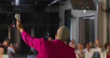 Cemaate hitap eden vaiz yakın plan, yükseltilmiş el ile canlı enerji, kapalı kilise ayarları, ruhsal bağlantı ve grup ibadetleri, duadaki dinamik liderlik