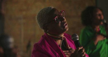 Şarkıcılar evanjelik kilise toplantısı sırasında tutkuyla şarkı söylerler, Afrikalı kökenli kadınlar mikrofon tutarlar, kalpten ibadet ederler, ruhsal ses iletimi, ruhsal bağlantı.