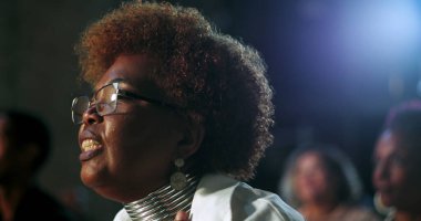 İbadet eden, gözlüklü, yansıtıcı takan ruhani bir kilise toplantısında inanç ve bağlılığını ifade eden bir kadının yakın çekimi.